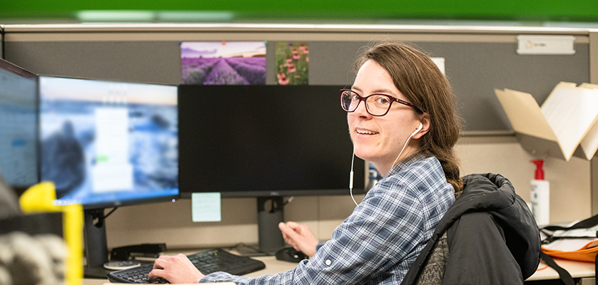 Employee sitting at computers listening to headphones