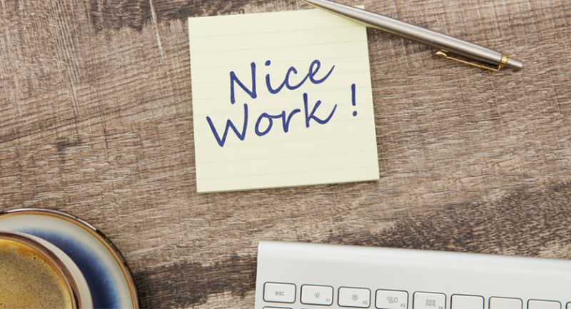 A note reading "nice work!" left on a work desk, showing appreciation in the workplace.