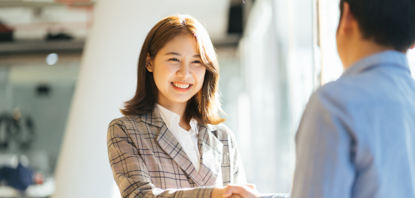 A woman shaking a man's hand smiling.